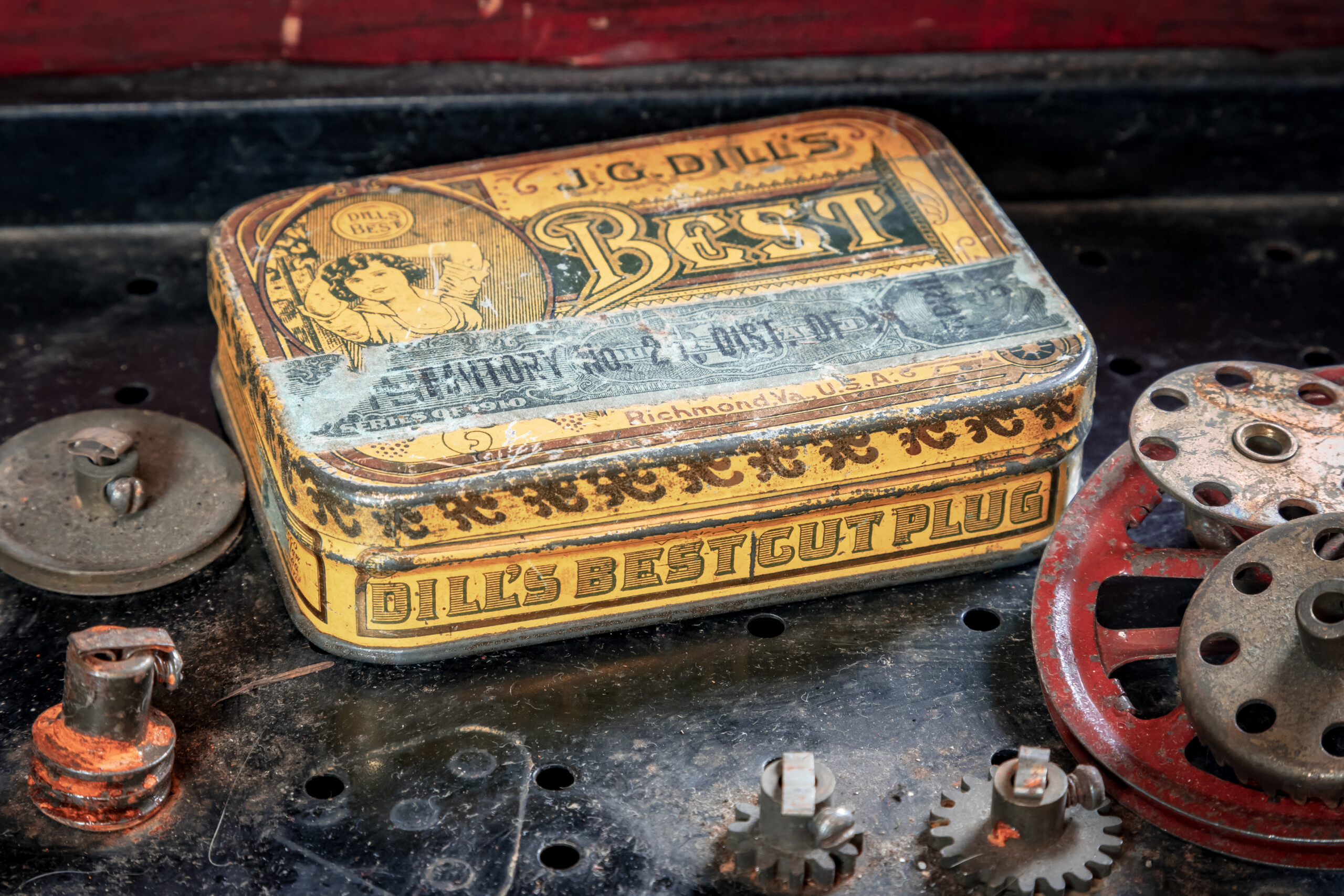 An old tobacco tin reused to hold nuts and bolts, showing packaging continuing to have value after the original product is gone